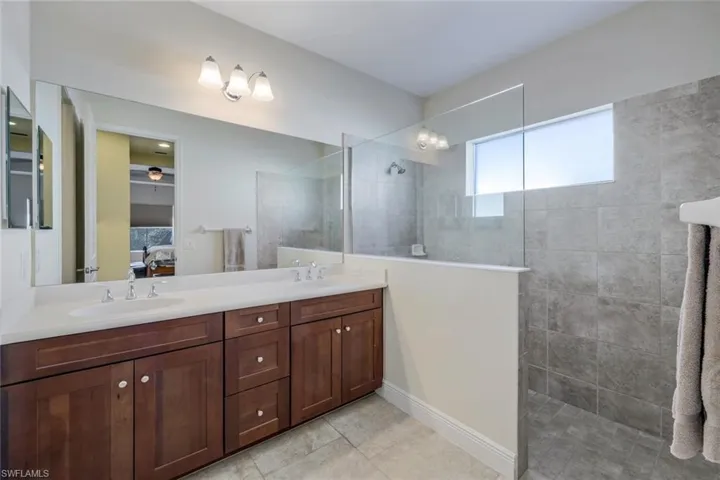 Full bathroom featuring healthy amount of natural light, double vanity, walk in shower, and ensuite bathroom