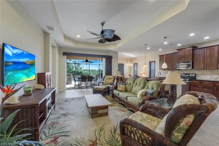 Living room featuring a tray ceiling, light tile patterned floors, ceiling fan, and recessed lighting