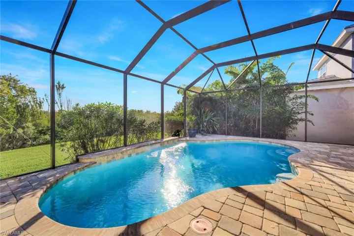Swimming pool with a sunroom, a lanai, and a lawn