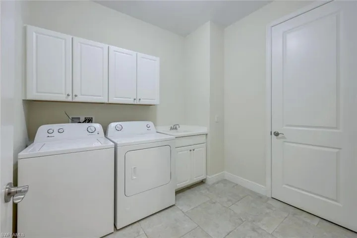 Washroom with cabinet space, independent washer and dryer, and light tile patterned floors