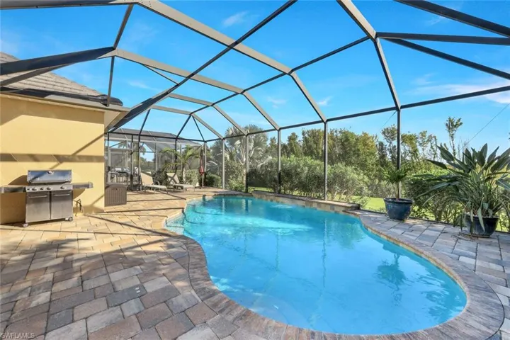 Outdoor pool with a lanai, a sunroom, grilling area, and a patio area