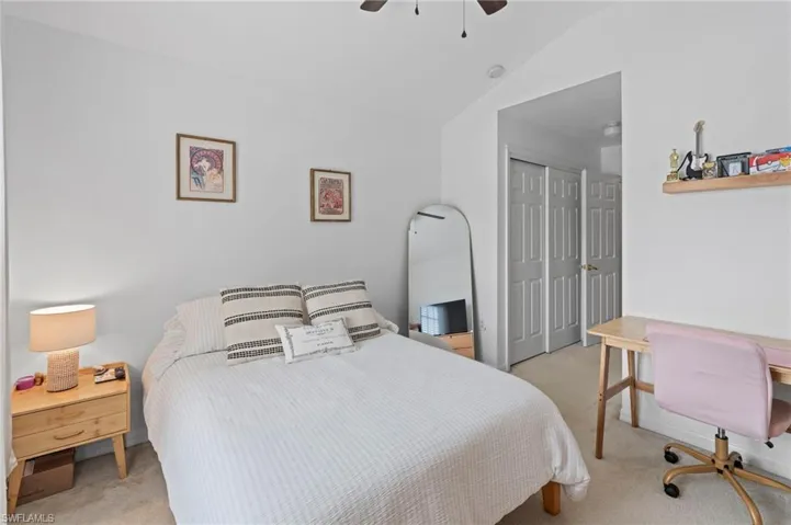 Bedroom featuring light carpet, a closet, lofted ceiling, ceiling fan, and a desk
