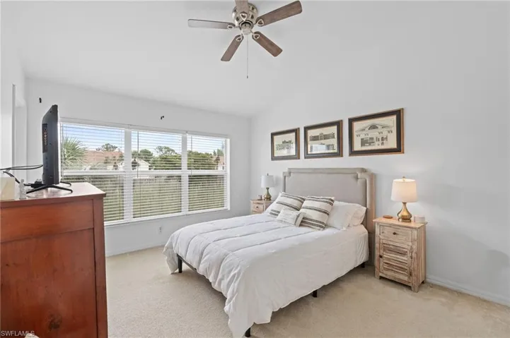 Bedroom featuring light colored carpet, lofted ceiling, and ceiling fan