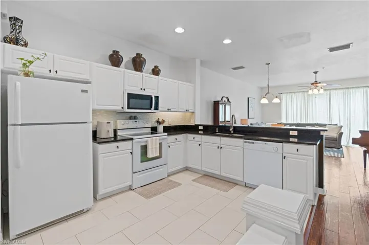 Kitchen with white appliances, white cabinets, and tasteful backsplash