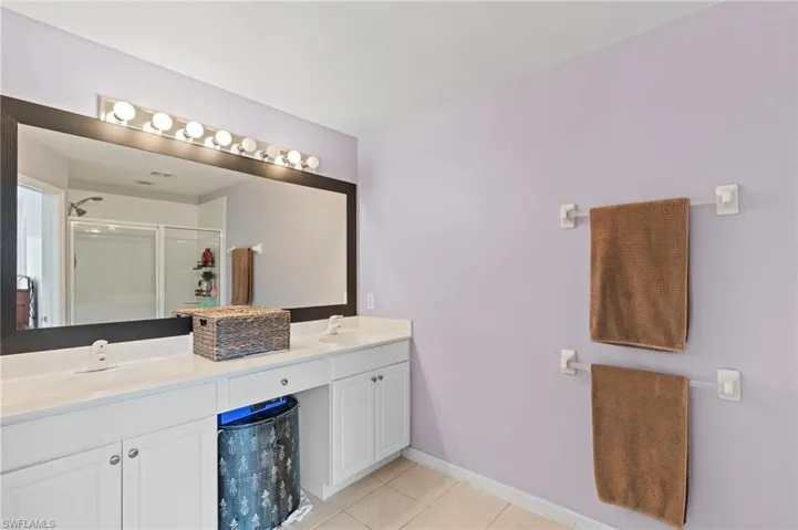 Bathroom with a stall shower, double vanity, and light tile patterned flooring