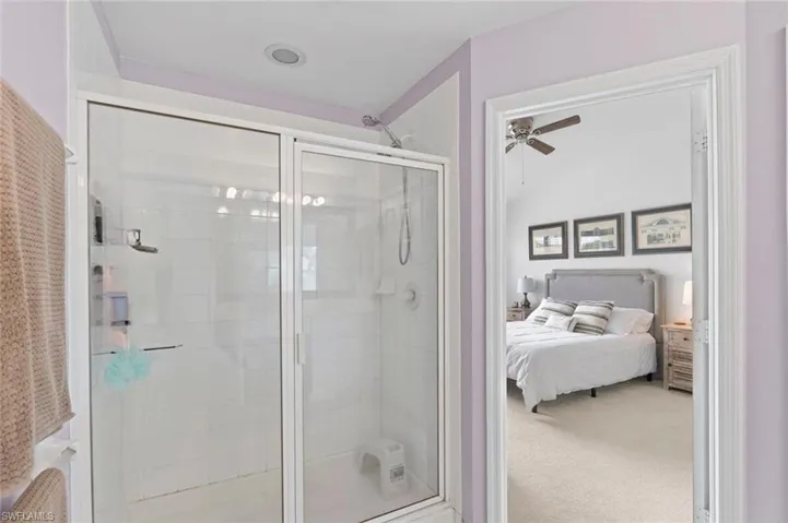 Bathroom with ensuite bathroom, carpet floors, a shower stall, and a ceiling fan