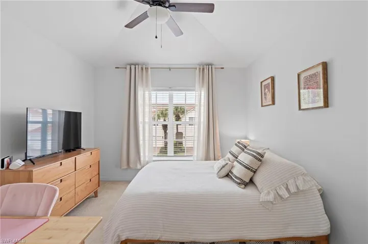 Bedroom with light colored carpet, ceiling fan, and vaulted ceiling