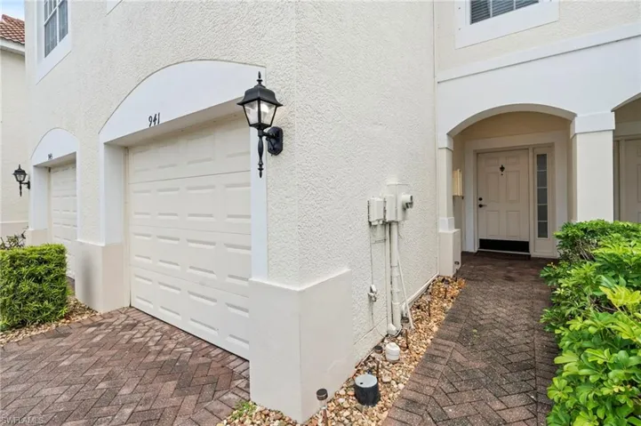 View of exterior entry with stucco siding, a garage, and decorative driveway