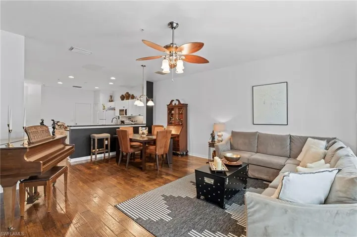Living room featuring dark wood-style flooring, ceiling fan, and recessed lighting