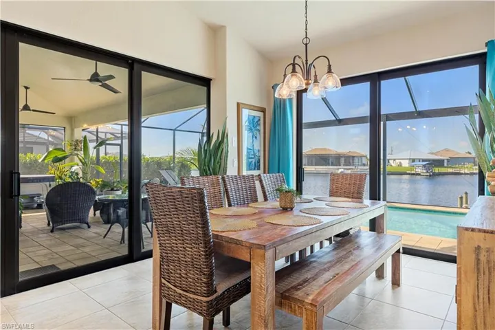Dining area featuring a water view, ceiling fan with notable chandelier, and light tile patterned floors