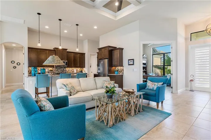 Living room with light tile patterned flooring, beam ceiling, coffered ceiling, and a high ceiling