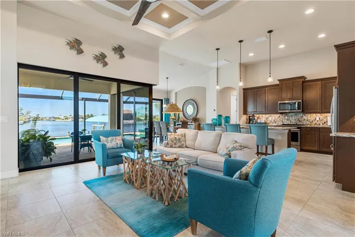 Tiled living room featuring beamed ceiling, french doors, a high ceiling, a water view, and coffered ceiling
