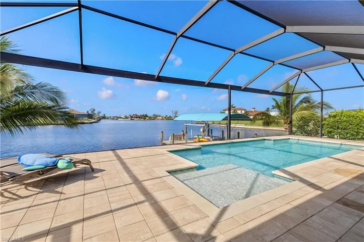 View of swimming pool with a patio, a water view, and glass enclosure
