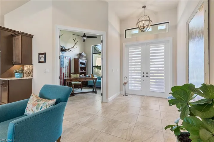 Foyer with a high ceiling, french doors, ceiling fan with notable chandelier, and light tile patterned floors