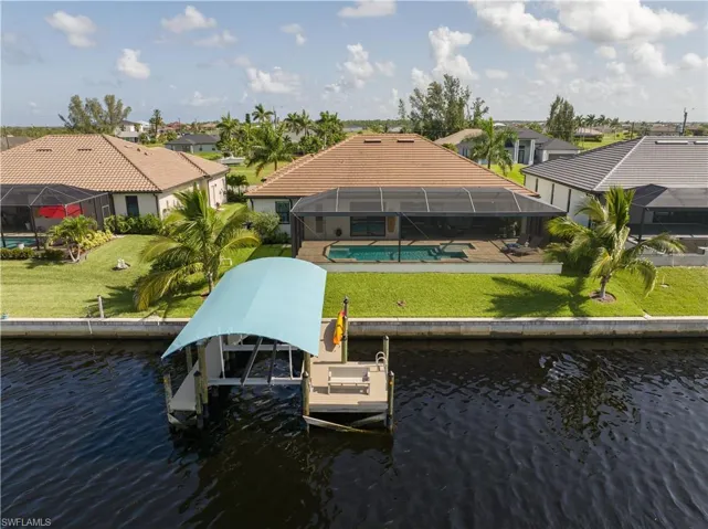 Dock area with a water view, a yard, and glass enclosure