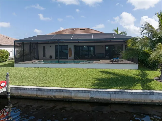 Rear view of house with a patio, glass enclosure, and a yard