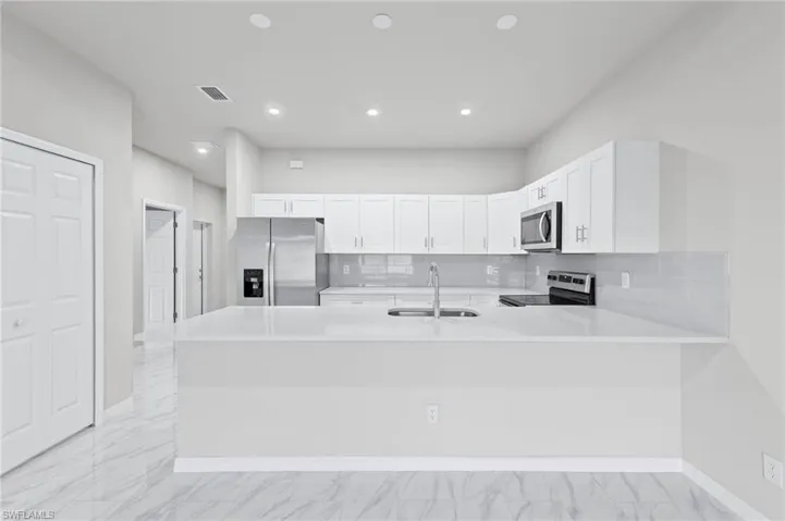 White quartz countertops, stainless steel appliance package with all white cabinetry.