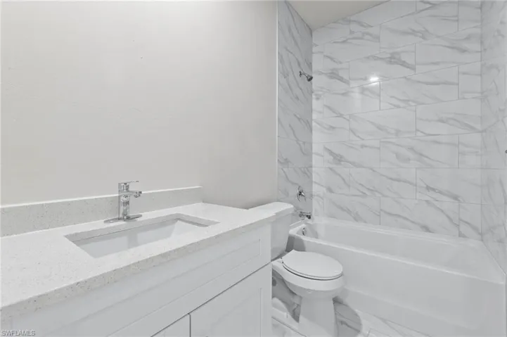 White quartz countertops with tub to ceiling tile.