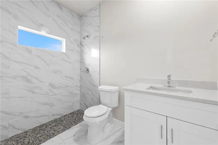 White countertop with natural light in the stand up shower composing of floor to ceilings tile.