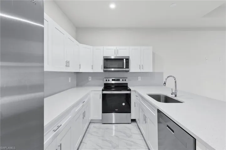 White quartz countertops, stainless steel appliance package with all white cabinetry.