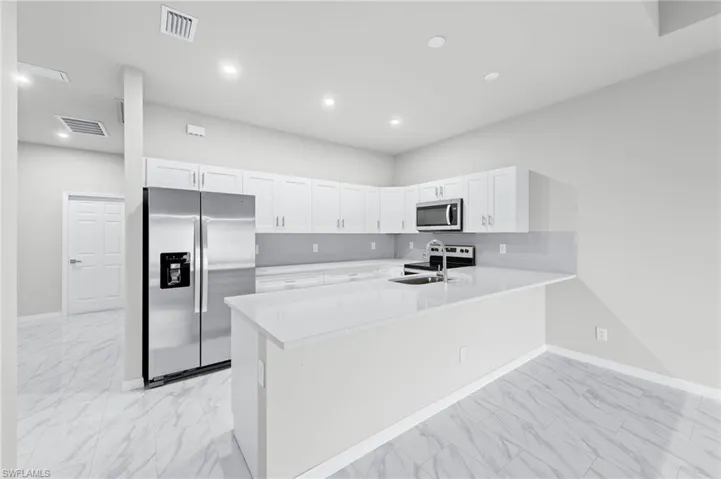 White quartz countertops, stainless steel appliance package with all white cabinetry.