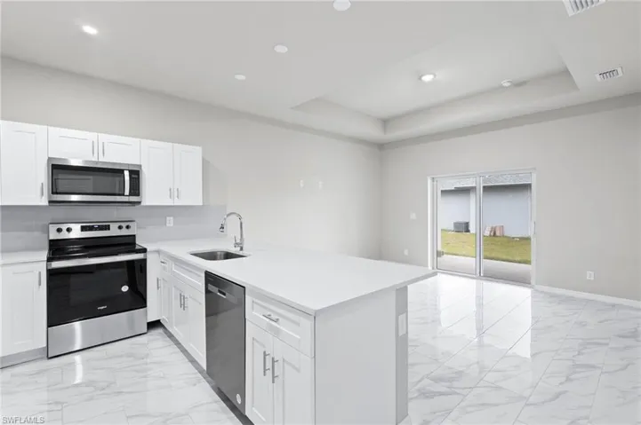 White quartz countertops, stainless steel appliance package with all white cabinetry.