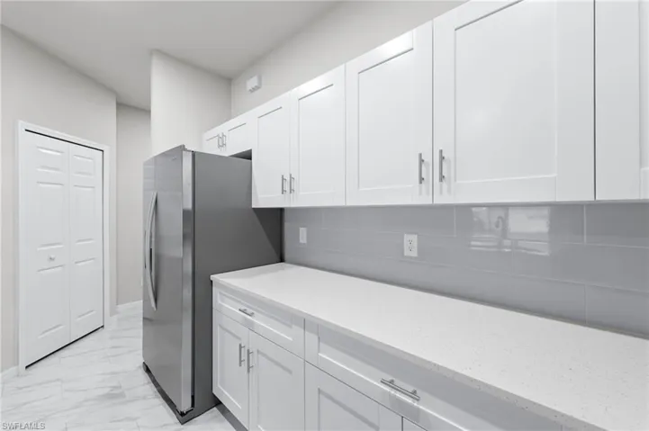 White quartz countertops, stainless steel appliance package with all white cabinetry.