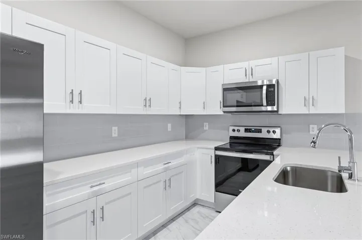 White quartz countertops, stainless steel appliance package with all white cabinetry.