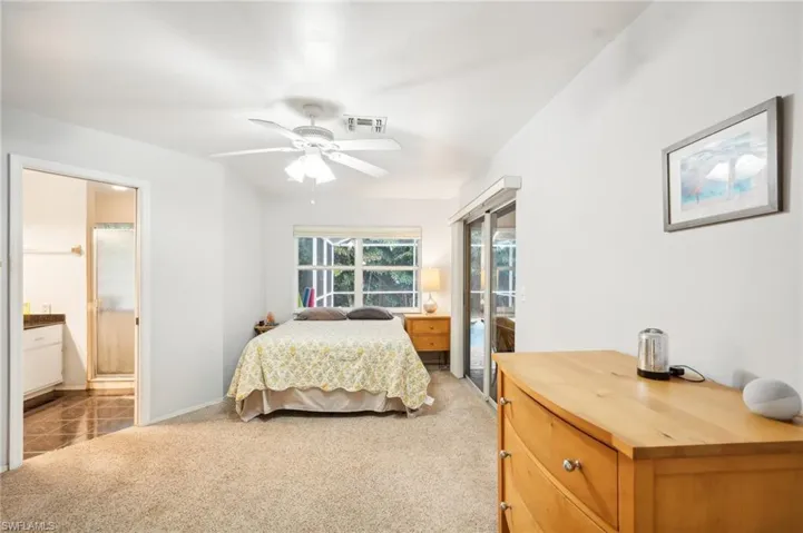 Bedroom with light carpet, ensuite bathroom, and ceiling fan