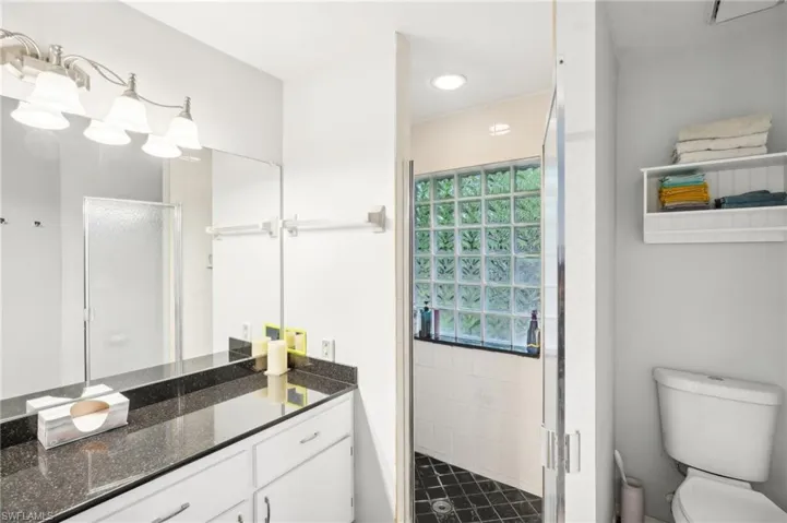 Bathroom with vanity, toilet, and a shower with door