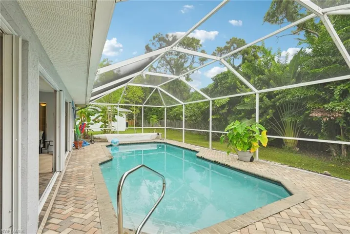 View of swimming pool featuring a patio, glass enclosure, and a yard