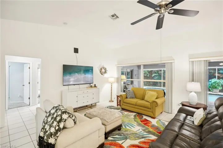Tiled living room featuring ceiling fan and high vaulted ceiling