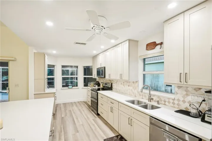 Kitchen featuring ceiling fan, sink, stainless steel appliances, light hardwood / wood-style floors, and decorative backsplash