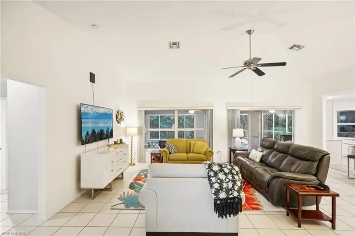 Tiled living room with ceiling fan and high vaulted ceiling