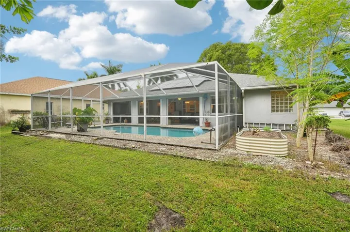 Back of house with glass enclosure, a patio, and a lawn