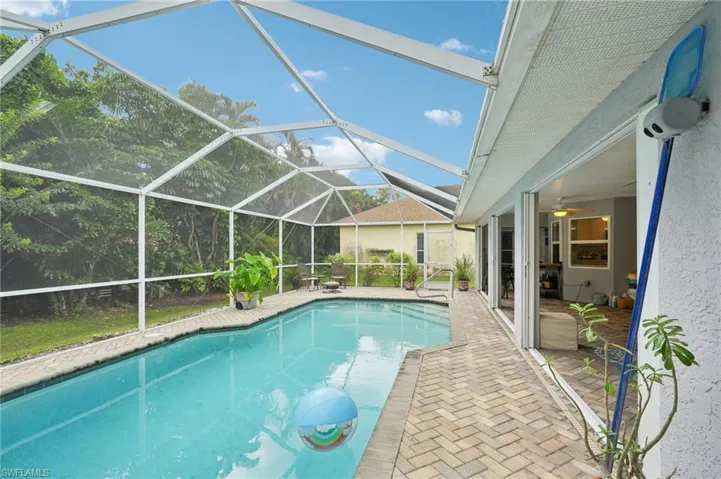 View of pool featuring ceiling fan, glass enclosure, and a patio