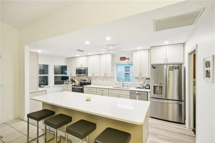 Kitchen featuring ceiling fan, white cabinets, sink, appliances with stainless steel finishes, and a breakfast bar area