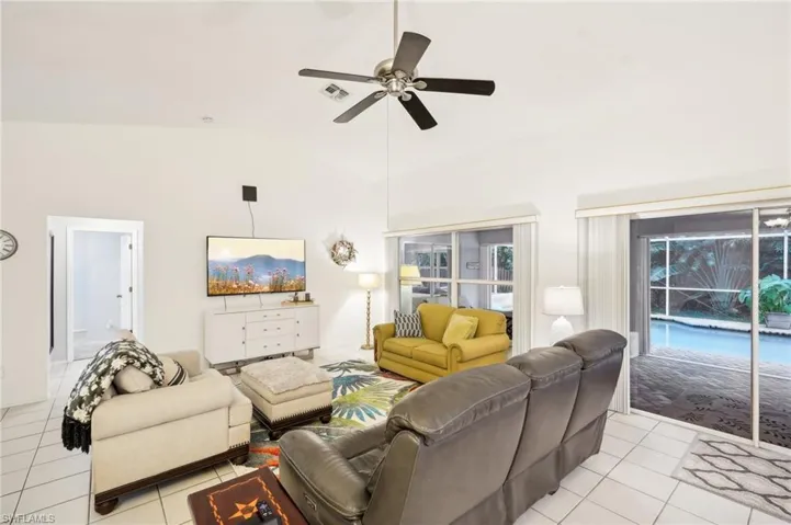 Living room featuring high vaulted ceiling, ceiling fan, and light tile patterned floors