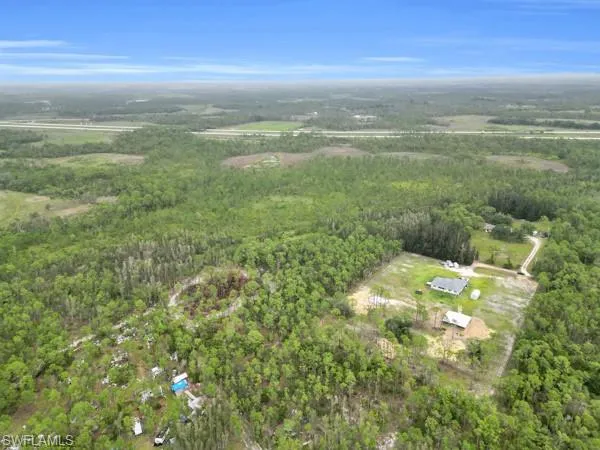 Aerial view of property and surrounding area featuring a forest