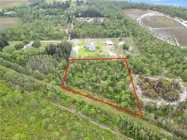 Aerial view of property's location featuring property parcel outlined and a forest
