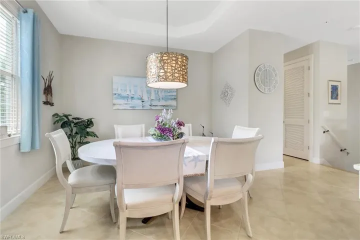 Dining area featuring a tray ceiling, cylindrical pendant lighting with a textured metallic finish, and ceramic tile flooring