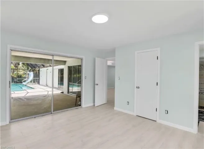 Unfurnished bedroom with access to outside, light wood-style flooring, a sunroom, and ensuite bath