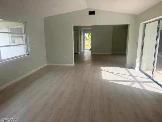 Unfurnished room with vaulted ceiling and light wood finished floors