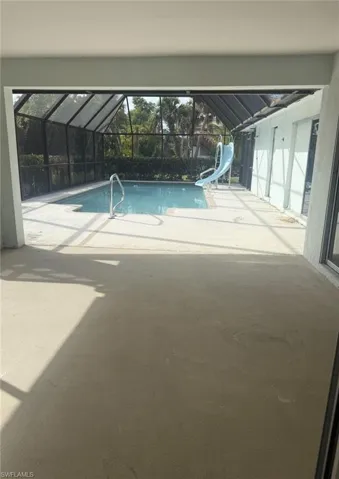 Swimming pool featuring a water slide, a patio area, glass enclosure, and a sunroom