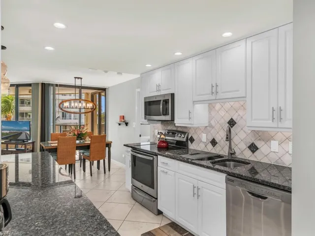Kitchen with pendant lighting, sink, white cabinetry, and stainless steel appliances