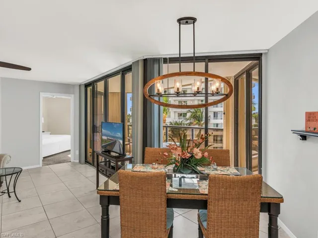 Dining area with floor to ceiling windows, light tile patterned flooring, and a chandelier