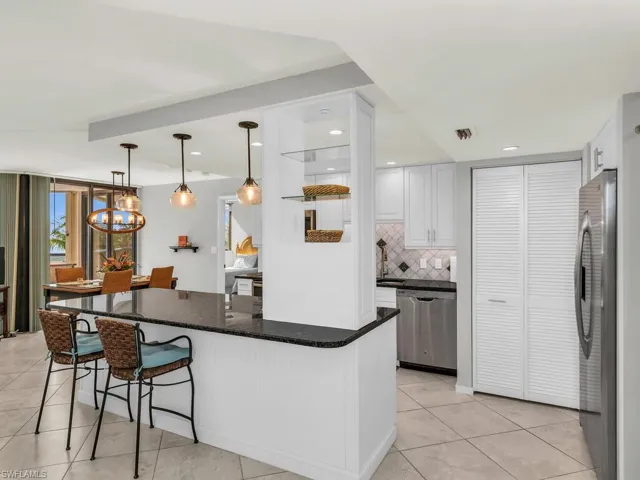 Kitchen with a kitchen bar, appliances with stainless steel finishes, tasteful backsplash, white cabinetry, and hanging light fixtures