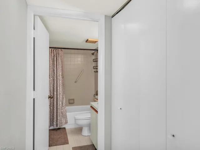 Full bathroom with tile patterned floors, vanity, toilet, and shower / bathtub combination with curtain