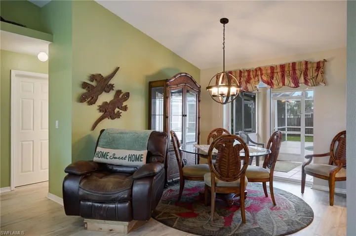 Dining space with a chandelier, wood finished floors, and vaulted ceiling