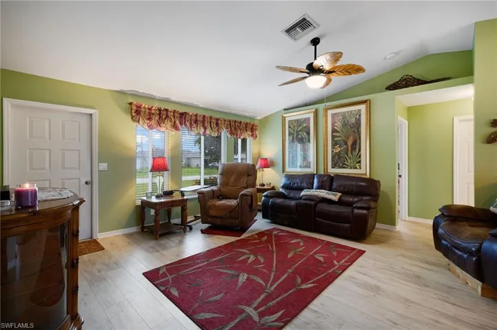Living room featuring lofted ceiling, a ceiling fan, and wood finished floors